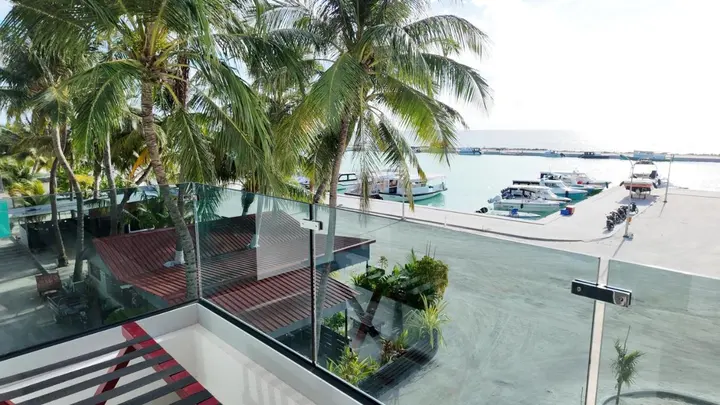 Glass-balustrade balcony overlooking palms and Maafushi harbour