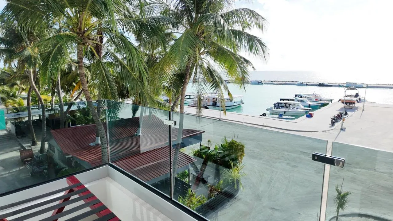 Glass-balustrade balcony overlooking palms and Maafushi harbour